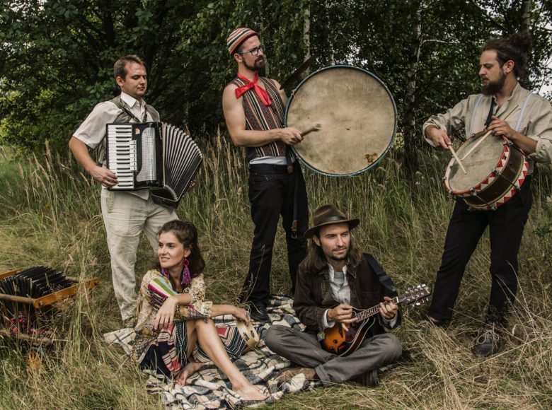 Zdjęcie przedstawiające członków zespołu Chwila Nieuwagi. Artyści pozują na łące.