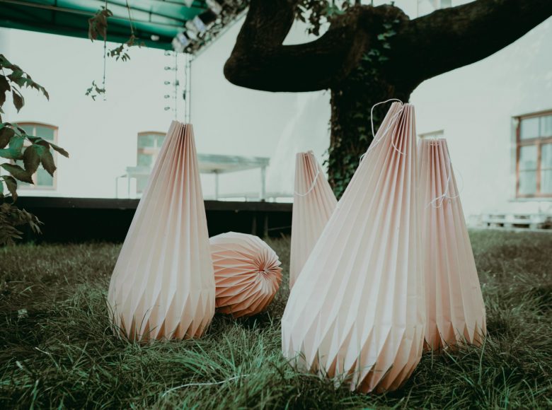 Zdjęcie. Pod drzewem stoją lampy wykonane z papieru.