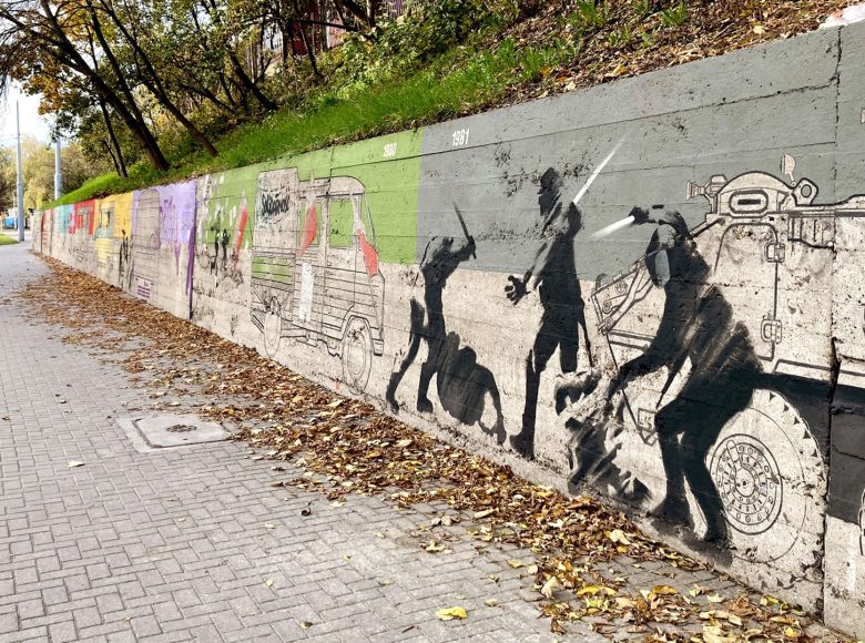 Mural namalowany na ulicznym murze. Przedstawia samochody produkowane w dawnej Fabryce Samochodów Ciężarowych w Lublinie oraz zomowców bijących pałami robotników.