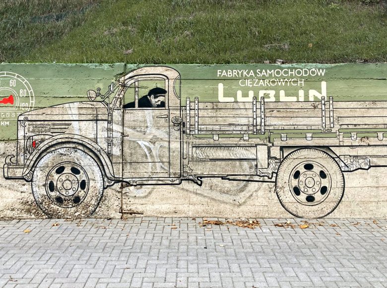 Mural namalowany na ulicznym murze. Przedstawia samochód ciężarowy z okresu PRL, z Lubelskiej Fabryki Samochodów Cieżarowych.