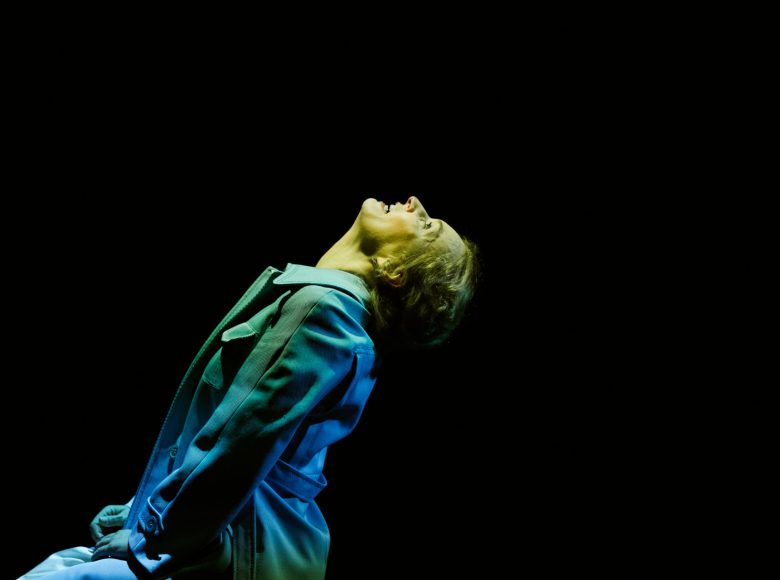 Kobieta w niebieskim stroju, widziana z profilu. Unosi twarz i patrzy do góry, lekko się uśmiecha.