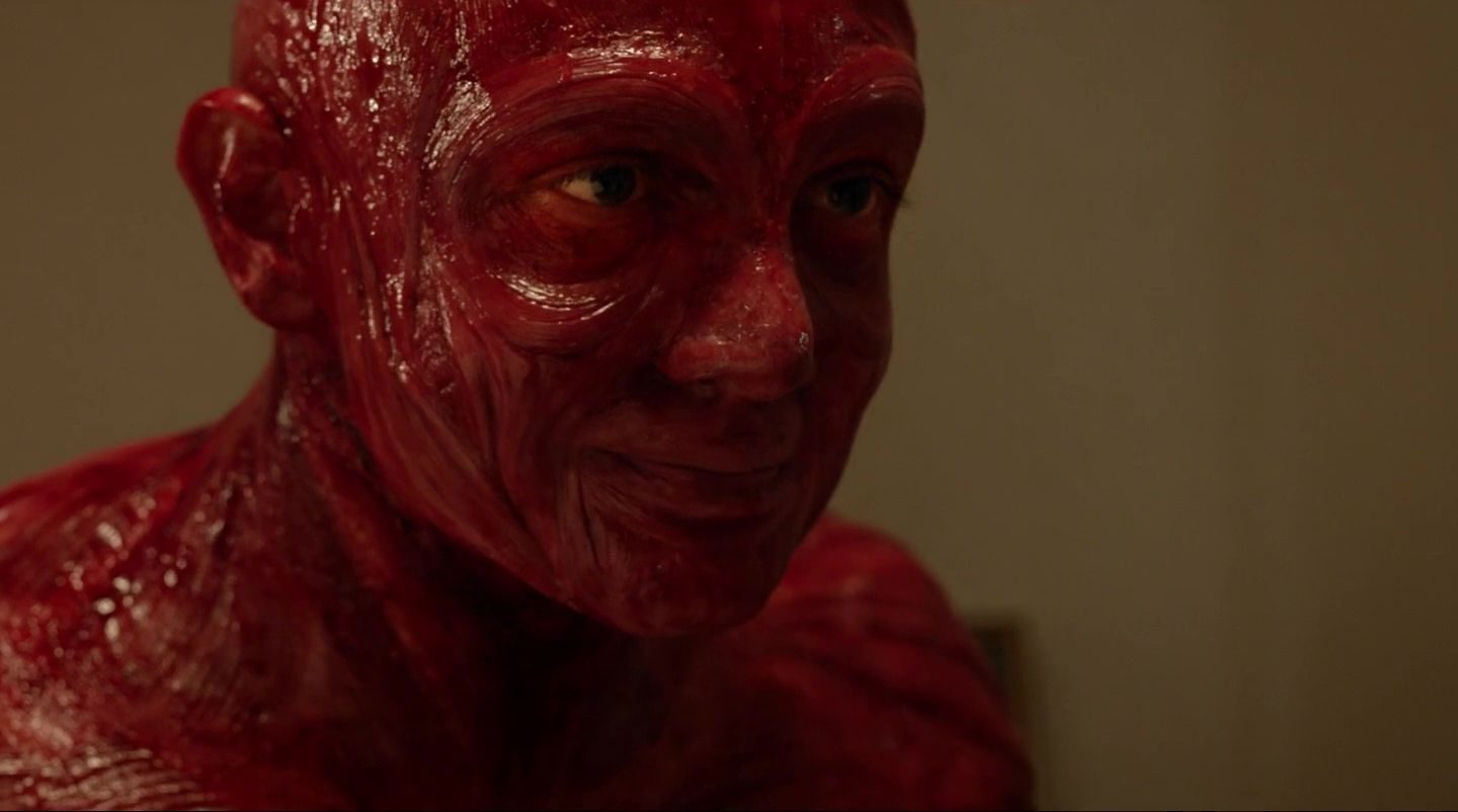 [ Kadr z filmu. Głowa i ramiona postaci bez skóry. Widoczne są błyszczące mięśnie i to wszystko, co człowiek ma pod skórą. ]