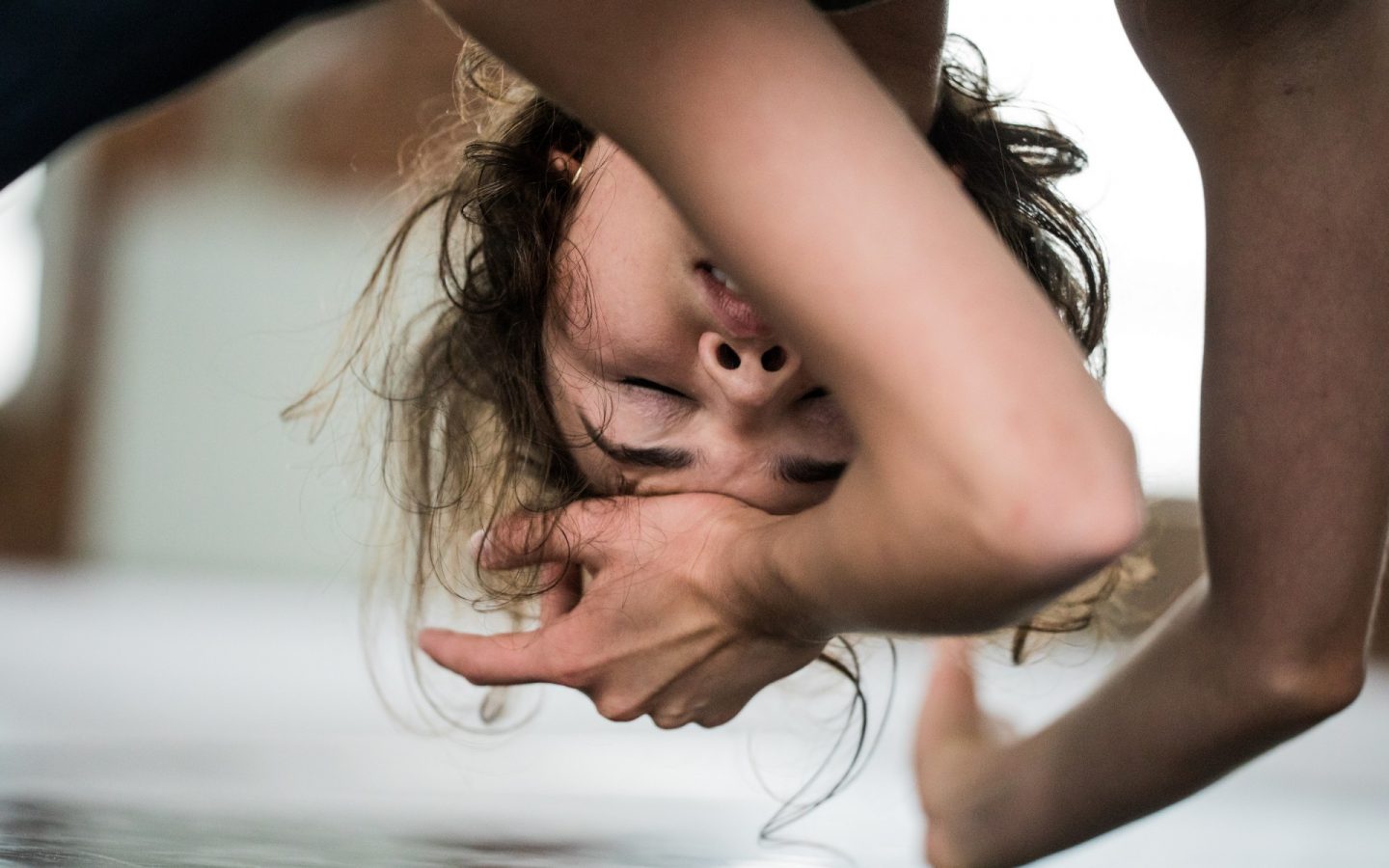 Zdjęcie. Zbliżenie na pochylona kobietę. Jedną rękę opiera o ziemię, drugą przykłada do czoła. Kobieta ma zamknięte oczy.