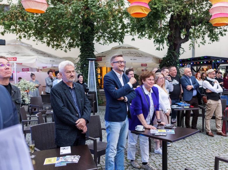 Wirydarz Centrum Kultury w Lublinie. Przestrzeń jest wypełniona ludźmi. Są elegancko ubrani, stoją i patrzą w tym samym kierunku.