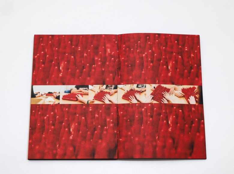 Zdjęcie otwartej książki. Zdjęcie czerwonej makiety ze stożkowatymi wypustkami. Fotografię na środku przecina poziomy kolaż zdjęć, który przedstawia makietę w różnych ujęciach i ręce, które jej dotykają.