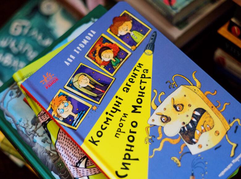Zdjęcie. Przedstawia kilka ułożonych obok siebie stosó książek dla dzieci z kolorowymi okładkami. Tytuły książek sa zapisane w jeżyku ukraińskim.