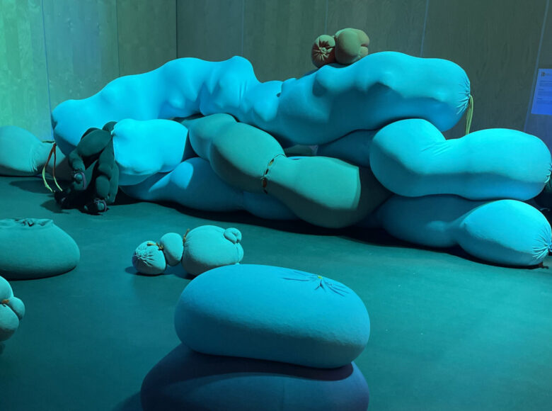 Kolorowa fotografia, dominująca jest kolorystyka niebieska. W jasnej przestrzeni ułożone są obiekty podłużne i okrągłe. Pojedyńczo lub w stosie jeden na drugim. Obiekty przypominają poduszki.