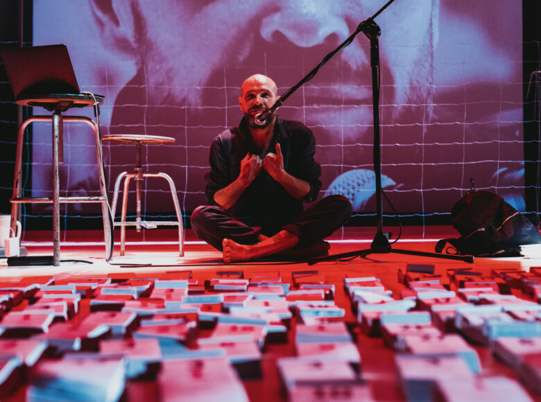 Zdjęcie. Mężczyzna siedzi na podłodze, przed nim leżą rozłożone w kilku rzędach kalendarze.