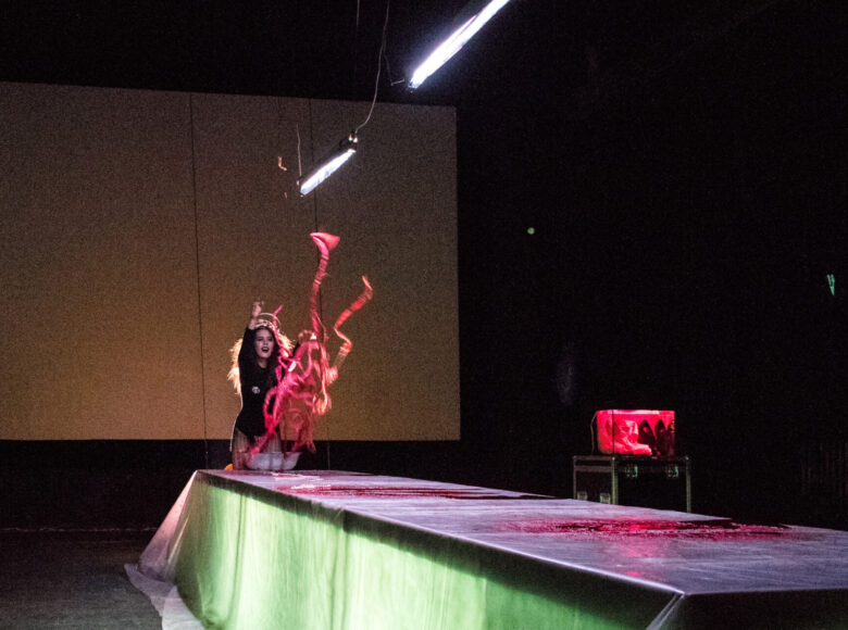 Kobieta z szaleństwem na twarzy wyrzuca w powietrze ludzkie wnętrzności. Stoi u szczytu podświetlanego stołu operacyjnego. Na stole są liczne ślady krwi. Scenerie oświetla jaskrawe światło sztuczne.