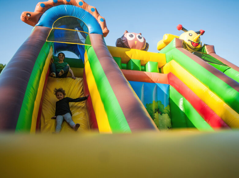 Zdjęcie. Dzieci bawią się na dmuchanej, kolorowej zjeżdżalni.