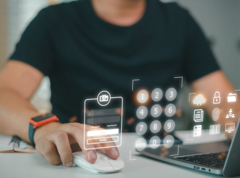 Zdjęcie. Osoba korzysta z laptopa. Przed komputerem wyświetla się trójwymiarowy interfejs.