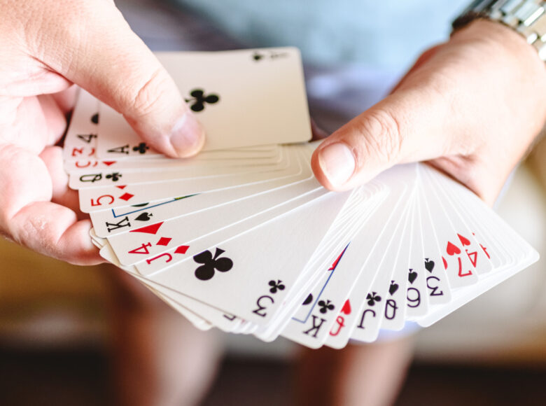 Zdjęcie. Mężczyzna trzyma w ręce talię kart.