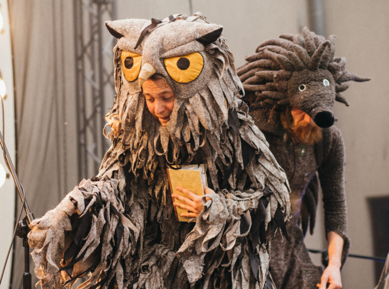 Zdjecie se spektaklu. Zbliżenie na aktorów w kostiumie sowy i jeża.