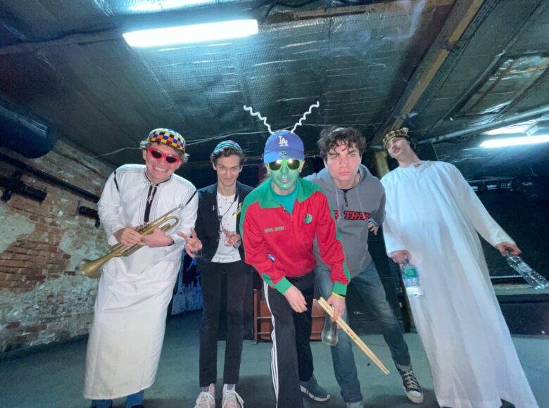 Zdjęcie. Grupa muzyków znajduje się w podziemiach. Jeden z nich jest przebrany za kosmitę.