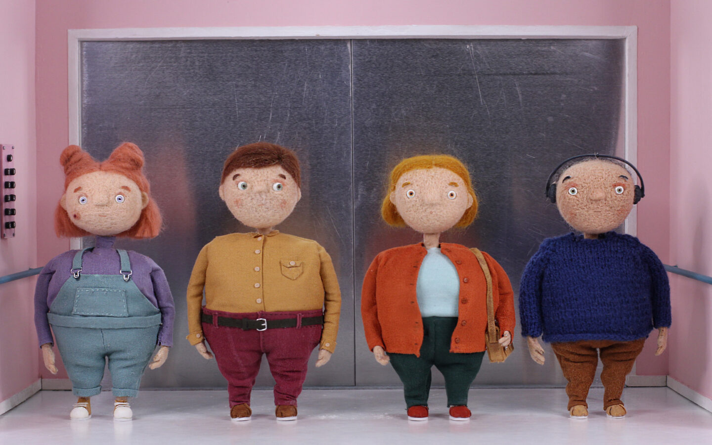 Kadr z filmu animowanego. Cztery postaci – lalki, stoją we wnętrzu windy. Dwie kobiety i dwóch mężczyzn stoi w szeregu. Każdy ma inne ubrania i włosy, ale wszystkie postaci są jednakowej wielkości i proporcji.