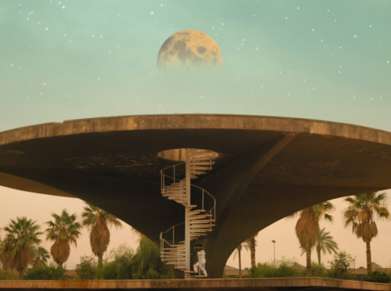 Kadr z filmu. Duża, betonowa konstrukcja w kształcie grzyba z płaskim kapeluszem, widziana od dołu. Na jego wierzch prowadzą spiralne, białe schody, po których wchodzi postać w skafandrze kosmonauty. W tle odległe palmy, błękitne niebo z gwiazdami i wielkim księżycem