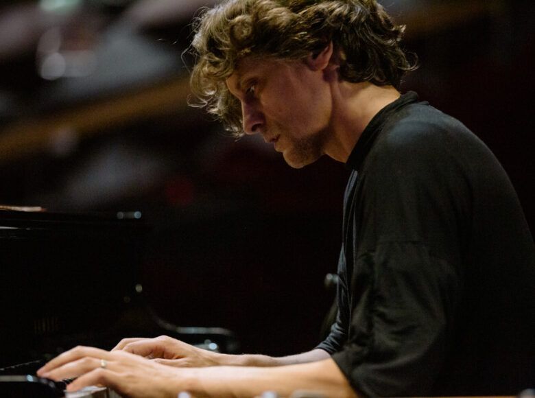 Zdjęcie. Zbliżenie na mężczyznę, który gra na pianinie. Jego twarz wyraża skipienie.