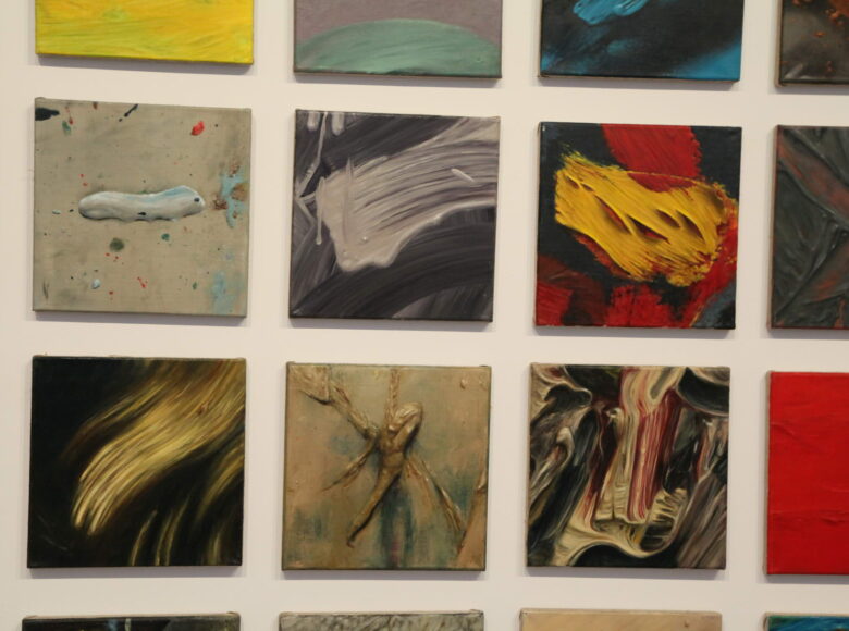 Zdjęcie przedstawia kolorowe, prostokątne grafiki zawieszone obok siebie na białej ścianie.