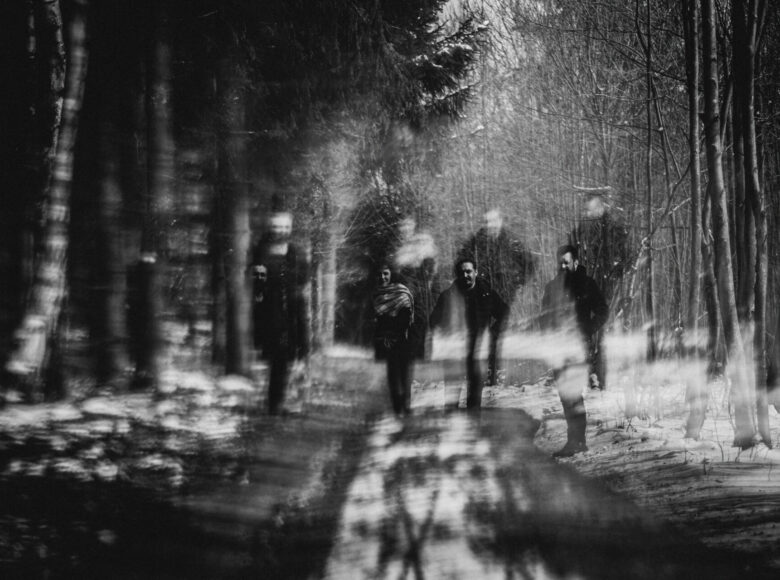 Czarno-białe zdjęcie przedstawia grupę ludzi, którzy idą leśną drogą.