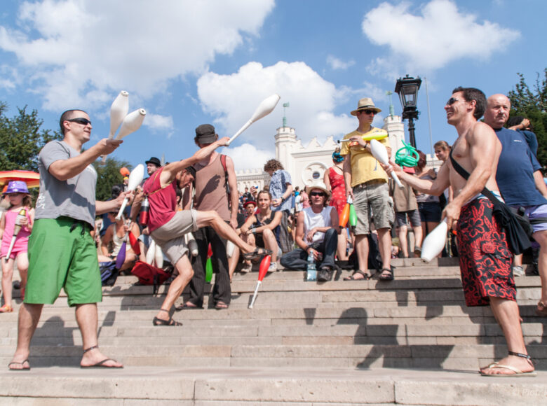 Letni dzień, schody Wzgórza Zamkowego w Lublinie. Na pierwszym planie kilku żonglujących chłopaków. Za nimi tłum ludzi siedzących na stopniach schodów.
