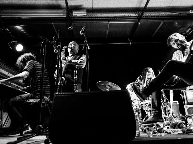 Czarno-białe zdjęcie przedstawia muzyków podczas koncertu.