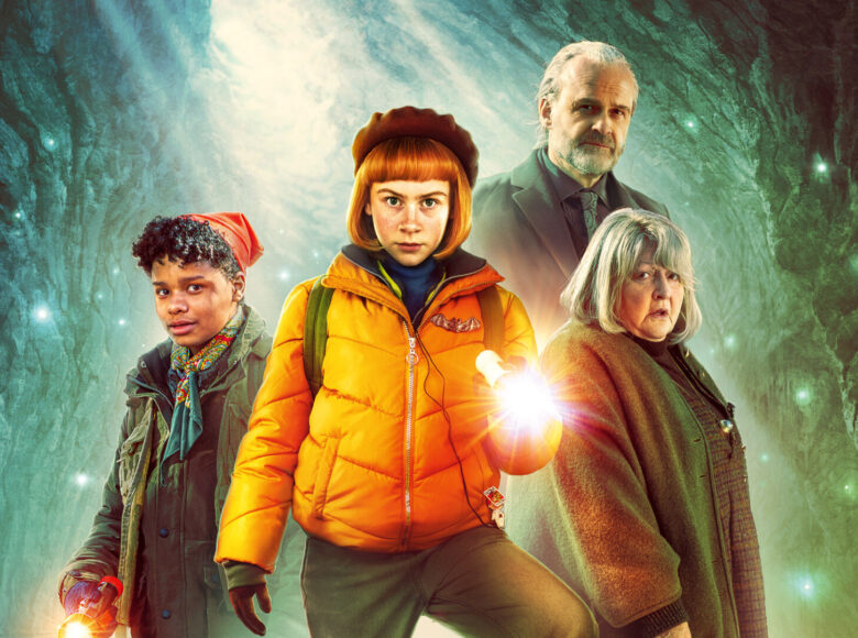 Fotos przedstawia plakat filmowy – na pierwszym planie tytułowa Nelly Rapp, w zółtej kurtce z przypinką w kształcie nietoperza, w berecie na głowie i z latarką w dłoni, wokół inne postaci z filmu. W tle światło jaskini.