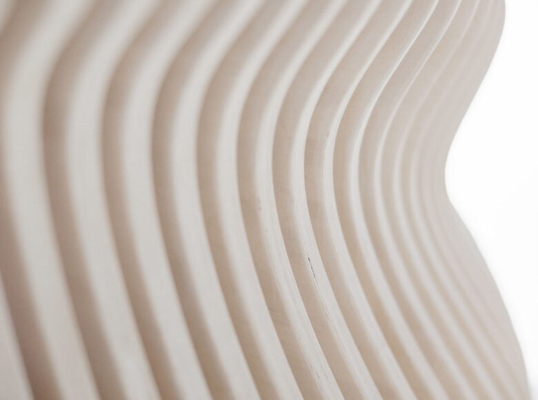 Na zbliżeniu fragment drewnianego stołu, wykonanego z cienkich drążków w kształcie fali.