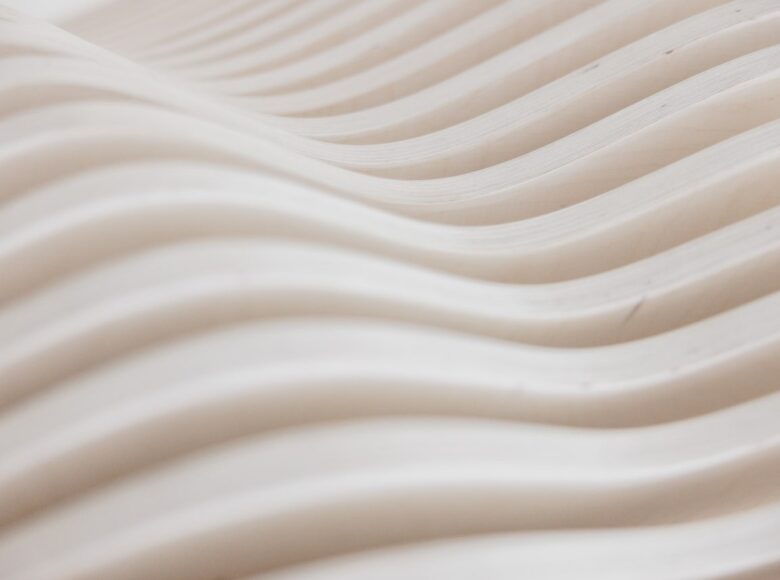 Na zbliżeniu fragment drewnianego stołu, wykonanego z cienkich drążków w kształcie fali.