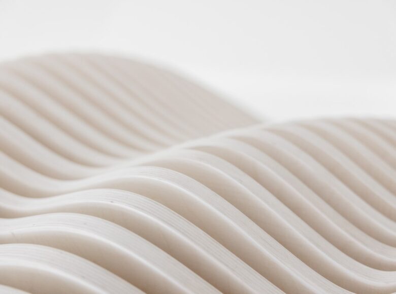 Na zbliżeniu fragment drewnianego stołu, wykonanego z cienkich drążków w kształcie fali.