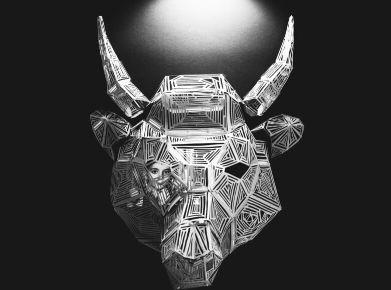 Czarno-biała grafika. Centralną jej część stanowi głowa żubra, która wydaje się być wycięta z papieru. W jednym z oczu zwierzęcia widać twarz dziecka.