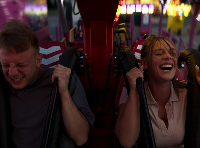 Kadr z filmu. Chłopak i dziewczyna w fotelach rollercoastera. Oboje trzymają się uchwytów zabezpieczeń, mają zamknięte oczy, w grymasach odsłaniają zęby.