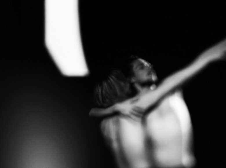 Czarno-biała fotografia. Rozmyta fotografia przytulonych do siebie dwóch osób.