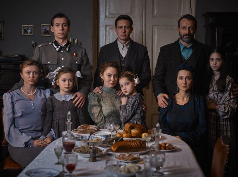 Fotos z filmu. Sceneria przedwojenna. W jadalni przy zastawionym stole zgromadzona grupa osób - trzy małżeństwa z dziećmi. Wszyscy mają odświętne stroje. jeden mężczyzn ubrany jest w mundur żołnierski.