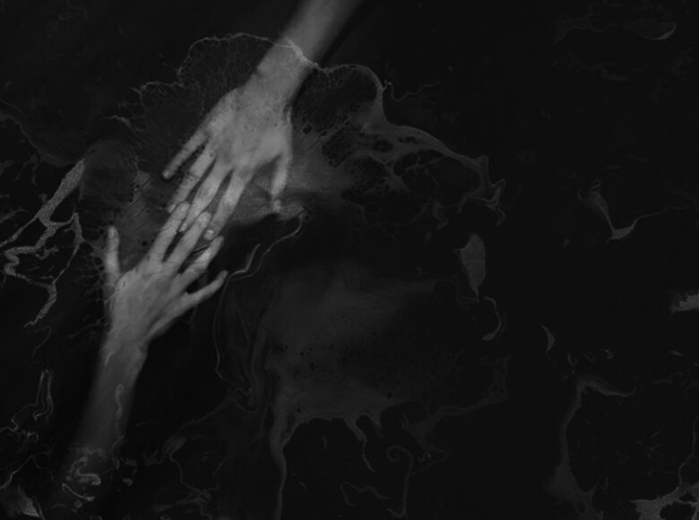 Czarno-biała fotografia. Dwie dłonie różnych osób zbliżone do siebie. Stykają się palcami. Całość lekko rozmazana.