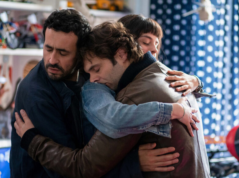 W centralnym punkcie fotografia przedstawia trzy osoby wzajemnie się przytulające. Wśród nich jest dwóch mężczyzn oraz kobieta. Wszyscy są bardzo czuli a uścisk jest wspierający. Tło rozmazane wskazuje na przestrzeń zabawy dla dzieci.