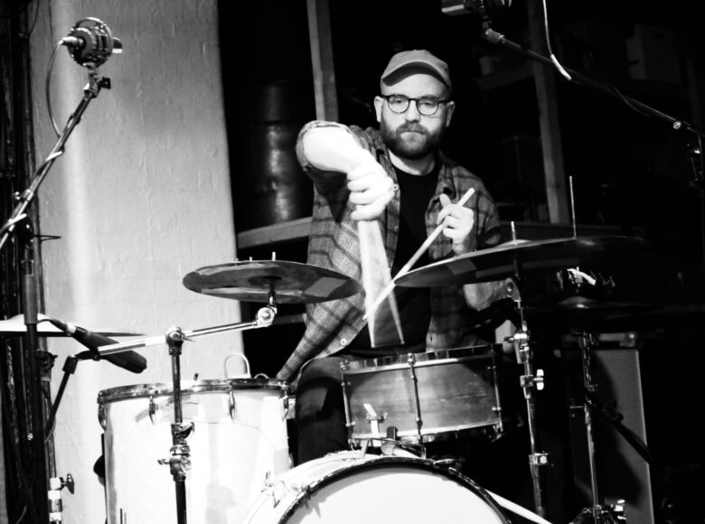 Na zdjęciu mężczyzna grający na perkusji na scenie.