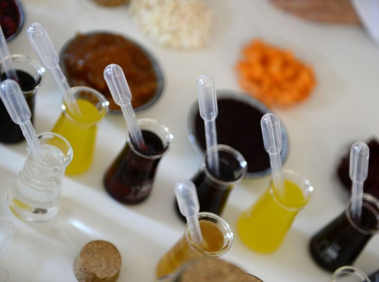 Zdjęcie przedstawia naczynka laboratoryjne z kolorowymi miksturami, menzurki.