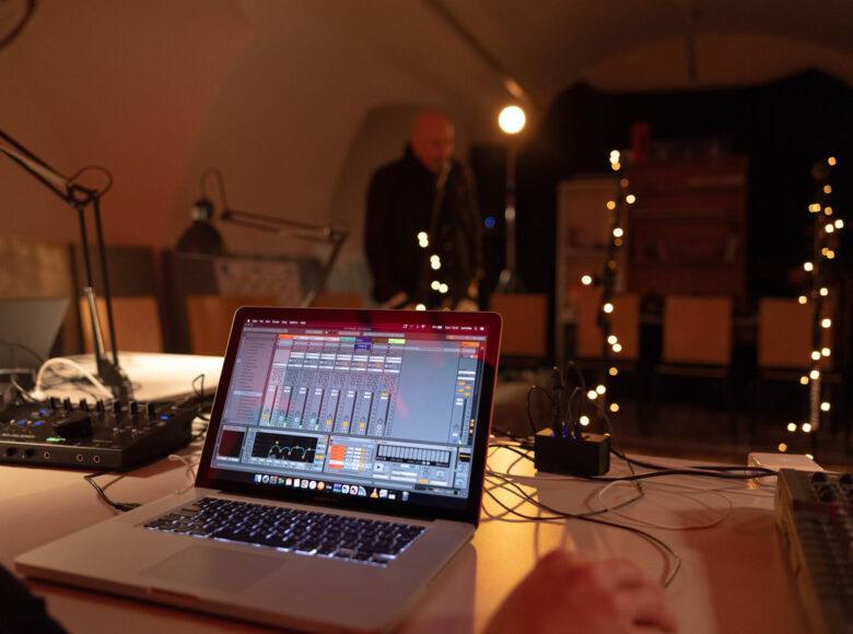 Kolorowe zdjęcie. Na pierwszym planie znajduje się stół, na którym leżą kable, konsole i laptop.