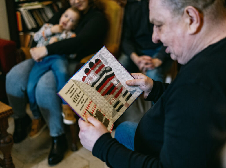 Zdjęcie przedstawia mężczyznę, który czyta książkę dla dzieci.