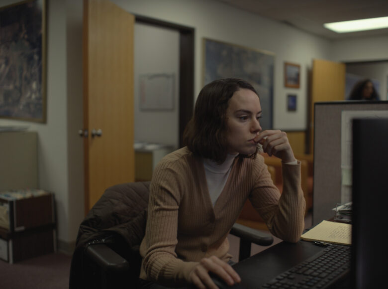 Kobieta w pokoju biurowym, przegląda zawartość komputera. Jest skupiona na pracy.