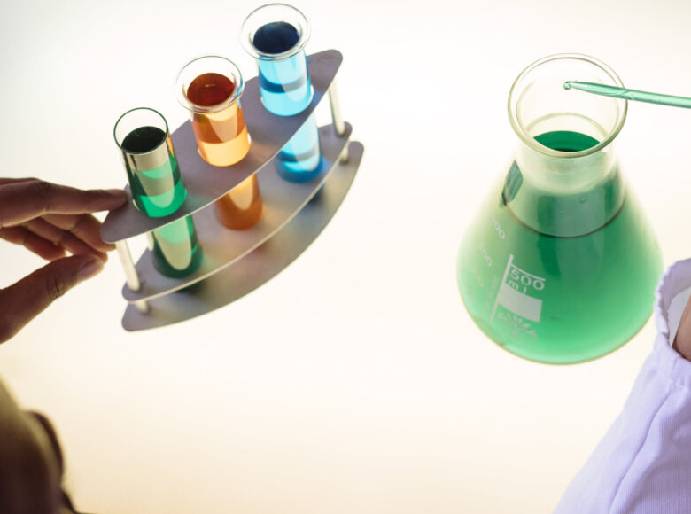 Zdjęcie przedstawia probówki i menzurki wypełnione kolorowymi płynami.