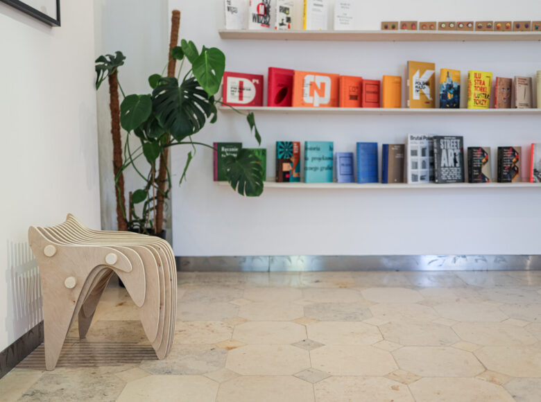 Na zdjęciu wnętrze sklepu w Centrum Kultury w Lublinie. Na białej ścianie półki z książkami.