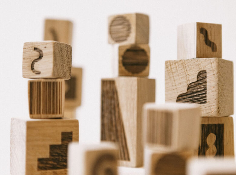 Na zbliżeniu znajdują się drewniane klocki ze stemplami, ułożone w klika wieżyczek.