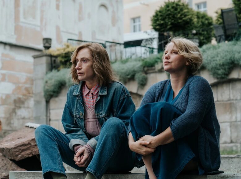 Mężczyzna i kobieta siedzą na schodach. Oboje są zamyśleni, jakby w ważnym temacie. Tonacja zdjęcia utrzymana w klimacie lat 80.tych ub. wieku.