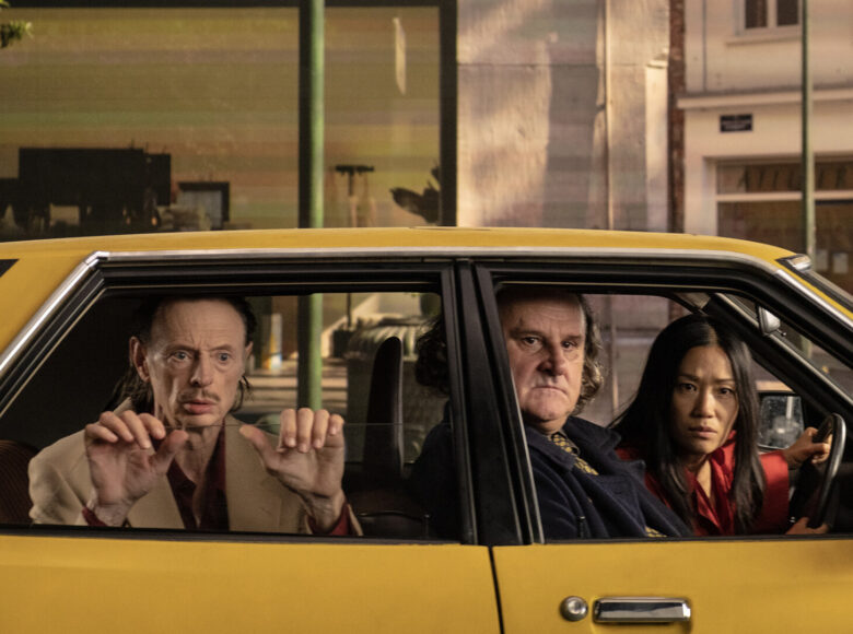 Dwóch mężczyzn i kobieta wyglądają przez boczne szyby miodowego auta. Są zdziwieni tym co widzą.