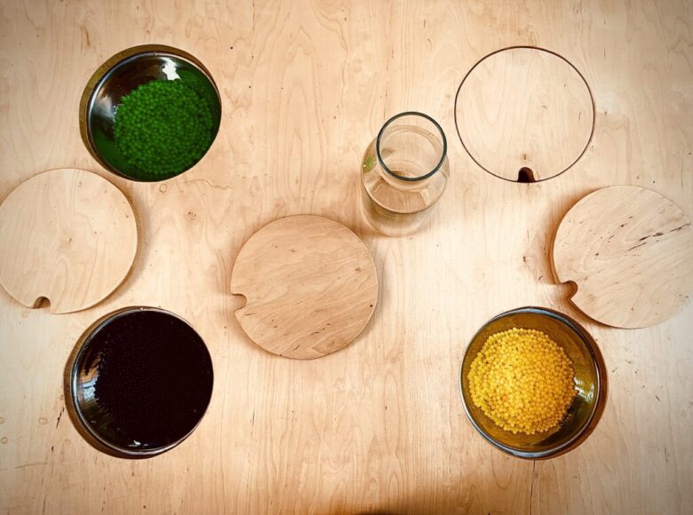 Widziany z góry stół z wpuszczonymi w blat miskami z kolorowymi kulkami.