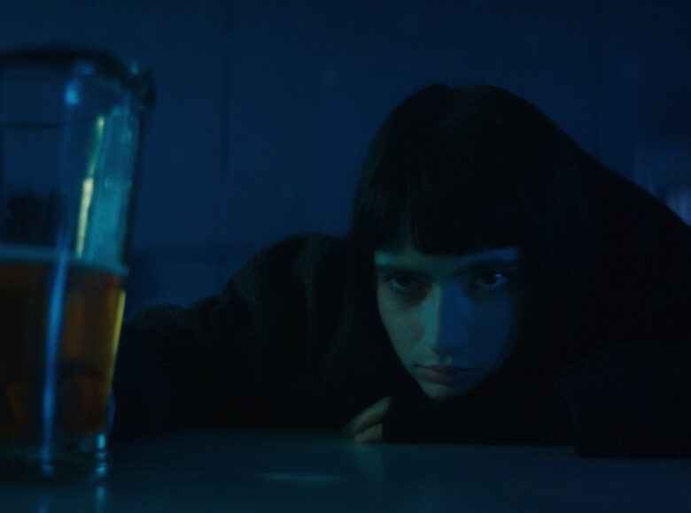 Ciemna fotografia to fotos z filmu, przedstawiający dziewczynę o czarnych krótkich włosach z grzywką. Dziewczyna opiera się o stolik i wpatruje w napój w szklance.