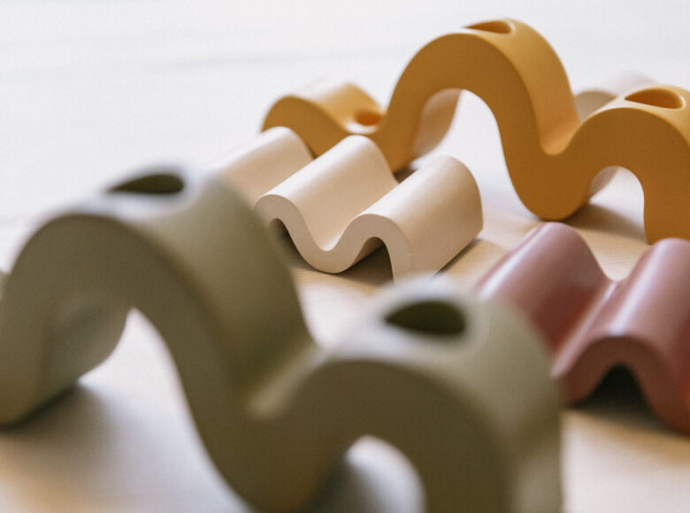 Kolorowa fotografia przedstawia małe figurki w kształtach fali. Figurki są różnych kolorów, takich jak: zielony, biały, czerwony, pomarańczowy.