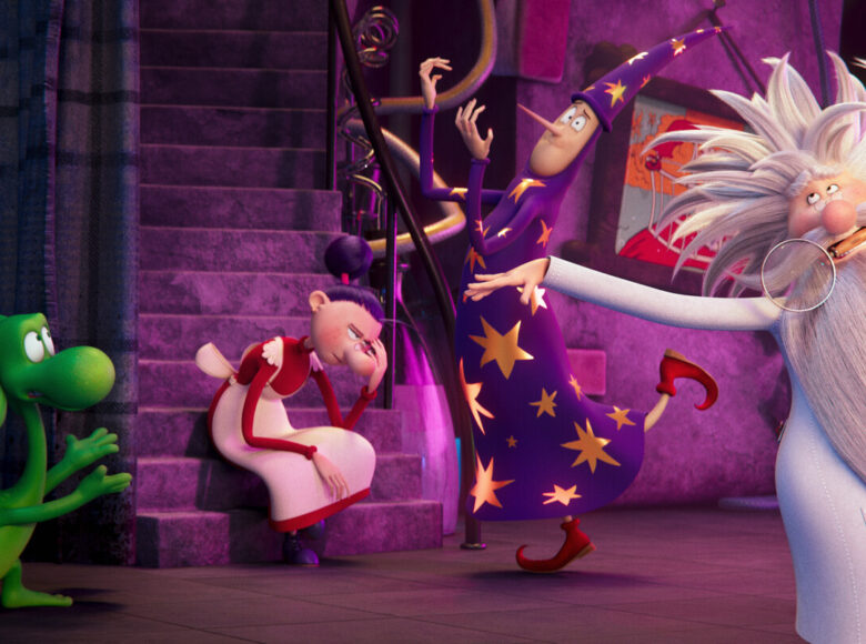 Kolorowa fotografia z przeważaniem koloru fioletowego przedstawia cztery postacie. Od lewej: zielony smok, kobieta w czerwono białej sukience, która siedzi na schodach, mężczyzna ubrany w fioletowy strój w złote gwiazdy niczym czarodziej, oraz starszy pan z siwymi włosami i długą siwą brodą. Mężczyzna w dłoni trzyma lupę i ubrany jest w biały fartuch.