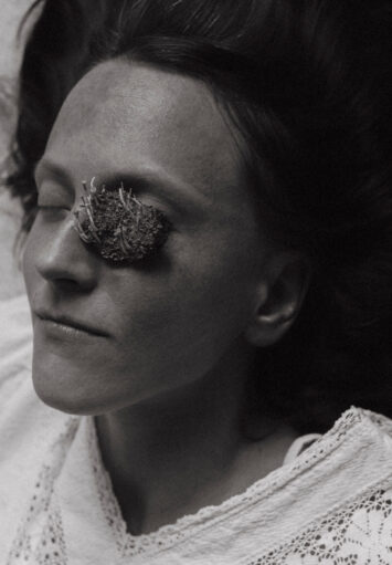 Zbliżenie na twarz kobiety. Kobieta ma zamknięte oczy. Na jednej z powiek kobiety leży niewielki organiczny przedmiot.